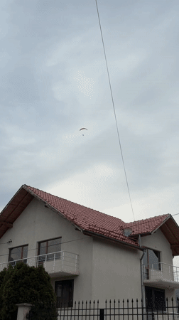 Paramotor pilot flies over Berkovitsa, Bulgaria amid cloudy skies
