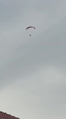 Paramotor pilot flies over Berkovitsa, Bulgaria amid cloudy skies