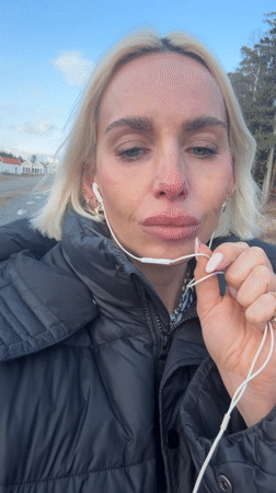 Woman speaks outdoors while wearing headphones in Strömstad