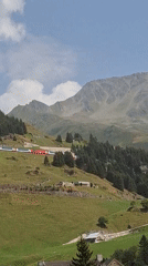 Red and white train climbing the hills above Andermatt