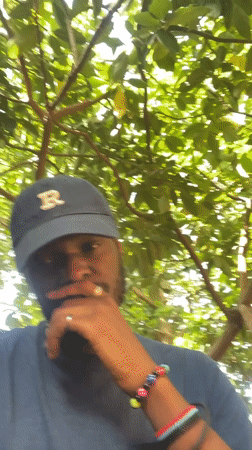 Man in blue cap photographed smoking under trees in Jos