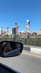 Vehicle crosses flag-lined bridge in sunny Yerevan