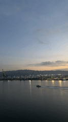 Evening harbor operations captured with motorboat, cargo ship activity