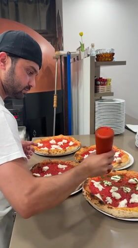 Pizza prep in a Trento kitchen, sauce being drizzled