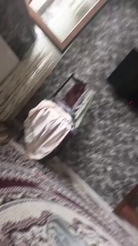 The video begins with a close-up shot of a partially filled plastic water bottle on a patterned carpet. The camera then pans upwards, showing a textured ceiling with what appears to be a fan and some sort of light fixture. The perspective shifts, and the video now shows a marbled surface, likely a countertop or window sill, with a white mug visible on the left side. The scene is brightly lit, suggesting natural light from a window. The camera movement is shaky, and the focus is inconsistent throughout the short clip. There are no people visible in the video.