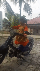Child plays on parked motorcycle outside Majasari kindergarten