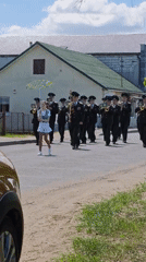 Military band performs marching music on rural street