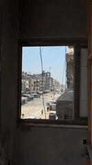 Residents collect water from a tanker truck amid Gaza's destruction.