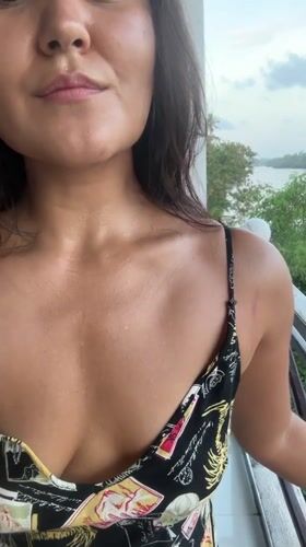 Woman with wet hair smiles from balcony in Peleana