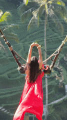 Woman in red dress swings over Tegallalang valley