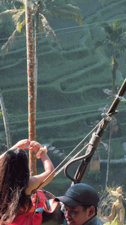 Woman in red dress swings over Tegallalang valley