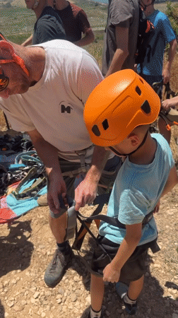 Adult helps child prepare for climbing in Zikhron Yaakov