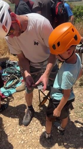 Adult helps child prepare for climbing in Zikhron Yaakov