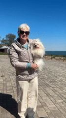 Woman walks small white dog on waterfront in Fontanka