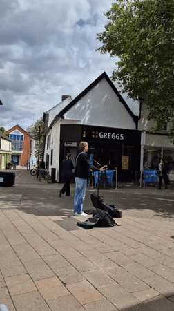 Street busker performs near cafe in West Suffolk town center
