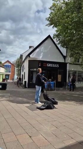 Street busker performs near cafe in West Suffolk town center