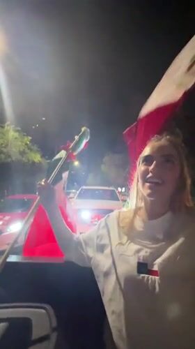 Mexican flags flying from a moving car in Mexico City at night