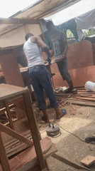 Men cutting wood outdoors in Ojomu, Nigeria