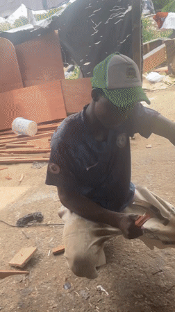 Men cutting wood outdoors in Ojomu, Nigeria