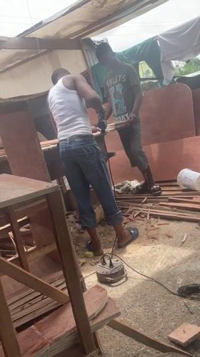 Men cutting wood outdoors in Ojomu, Nigeria