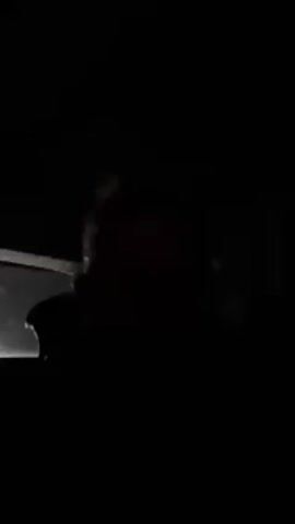 The video is recorded from inside a vehicle at night. The interior is dark, but the outline of a person in the driver's seat is visible. The camera angle is pointed towards the road ahead, though the darkness makes it difficult to discern any specific details about the surroundings. The only light source appears to be coming from inside the vehicle, faintly illuminating the driver. Music is playing in the background.