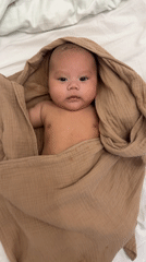 Baby with dark hair documented resting in crib