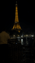 Golden-lit Eiffel Tower photographed at night from waterfront