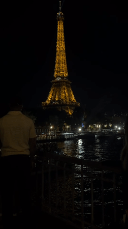 Golden-lit Eiffel Tower photographed at night from waterfront