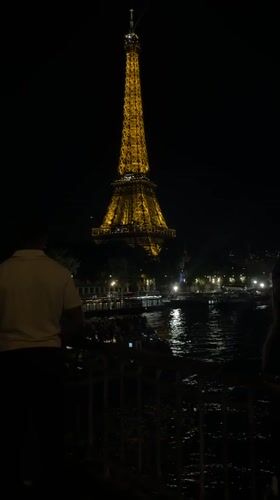 Golden-lit Eiffel Tower photographed at night from waterfront