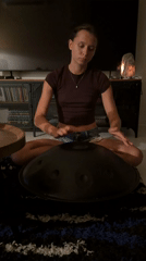 Woman plays handpan drum in dimly lit room, Chang Phueak