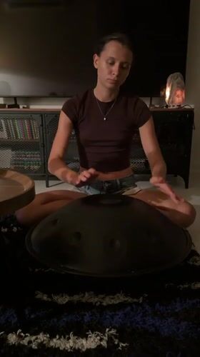 Woman plays handpan drum in dimly lit room, Chang Phueak