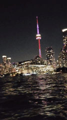 Toronto skyline glows at night, CN Tower in red and purple
