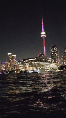 Toronto skyline glows at night, CN Tower in red and purple