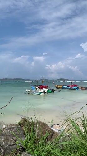 Morning beach scene with fishing boats and surfers in Mirissa