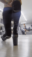 Woman approaches pole in studio wearing platform boots