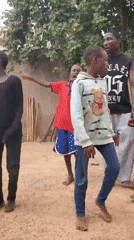 Children and adults in a rural outdoor gathering, dancing and drumming