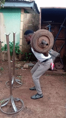 Man exercises with makeshift barbell outdoors in Akwanga, Nigeria
