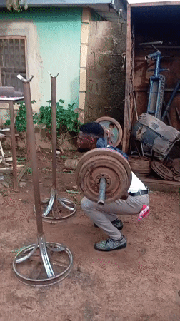 Man exercises with makeshift barbell outdoors in Akwanga, Nigeria