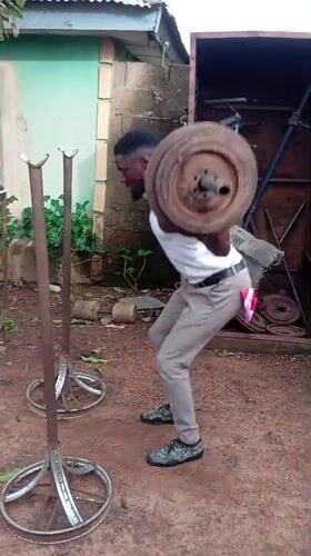 Man exercises with makeshift barbell outdoors in Akwanga, Nigeria