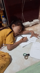 Girl writes on floor papers in Baron, Indonesia
