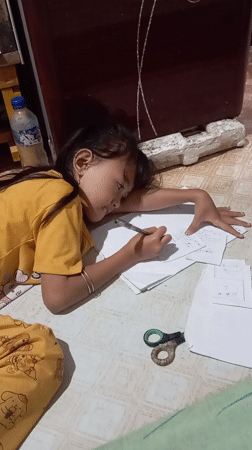 Girl writes on floor papers in Baron, Indonesia