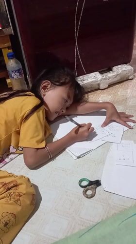 Girl writes on floor papers in Baron, Indonesia