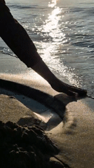 Person plays with sand and water on beach