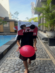 Child plays with cardboard box hat near Kuta pool