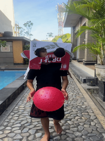 Child plays with cardboard box hat near Kuta pool