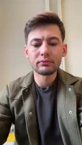 A medium shot shows a man wearing a green jacket and a grey t-shirt. He holds up a cocktail stirring spoon. He makes a surprised face with his mouth open. He says "Nice." The background is a plain, light colored wall with a doorframe.