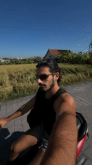 Man rides red scooter through rural North Kuta roadway