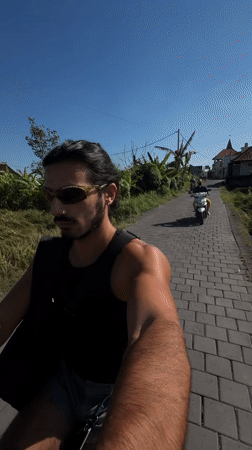 Man rides red scooter through rural North Kuta roadway