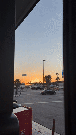 Golden sunset framed by dark vertical structures in Lost Hills