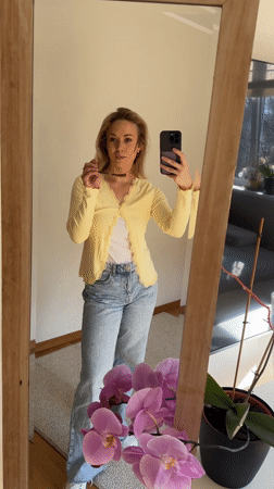 Woman takes mirror selfies in yellow cardigan, Riga